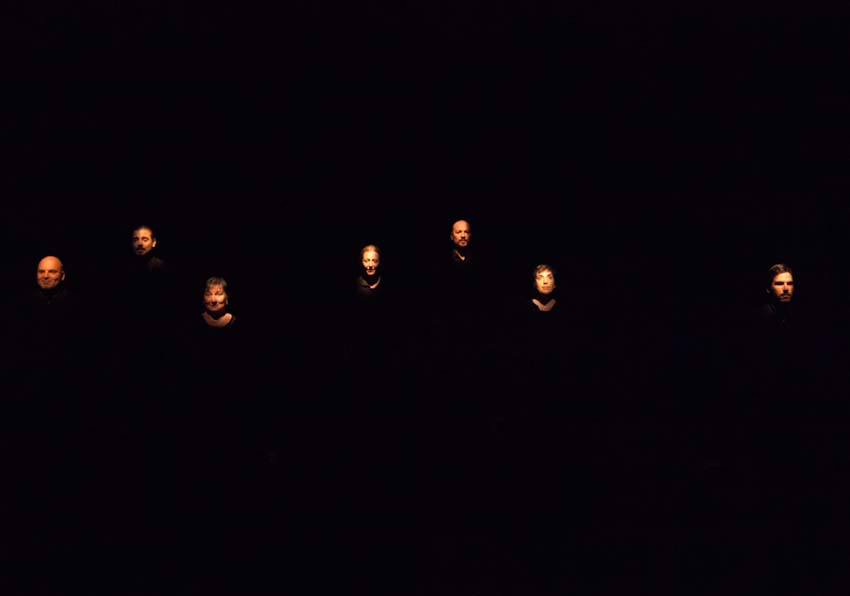 Set actors i actrius sobre fons negre il·luminant-los la cara